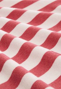 Tessuto di cotone con strisce ondulate rosse e crema, dalla texture morbida e aree alternate lisce e testurizzate.