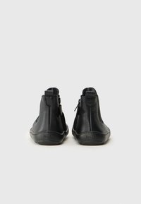 Black leather ankle boots featuring a textured surface, side zippers, and a low-profile rubber sole. Design is minimal with no visible branding.