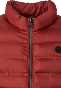 Rote Puffy-Jacke mit hohem Kragen, Reißverschluss und schwarzem Zubehör. Verfügt über genähte horizontale Paneele und ein rundes Logo auf der Brust.
