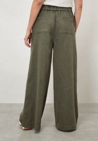 Pantalones verdes de pierna ancha con una cintura elástica, dos bolsillos traseros y una tela suave y texturizada. El dobladillo es recto y sin adornos.
