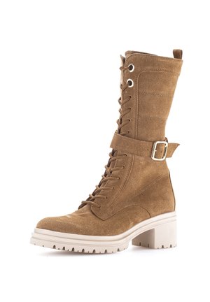 Brown suede lace-up mid-calf boot with a buckle strap and thick white rubber sole and block heel.