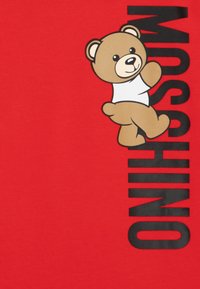 Rotes T-Shirt mit einem grauen Bärenmotiv und dem Wort "MOSCHINO" in fetten schwarzen Buchstaben. Weiches Baumwollmaterial mit glatter Textur.