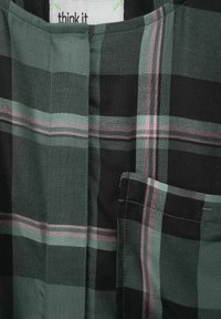 Tissu à carreaux vert, noir et rose, doté d'un col rond et d'une poche poitrine. Tissage texturé avec un motif à carreaux classique.