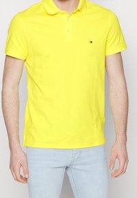 Geel polo shirt van katoen met een klassieke kraag, korte mouwen en een klein logo op de borst. Draagt met lichtblauwe jeans.