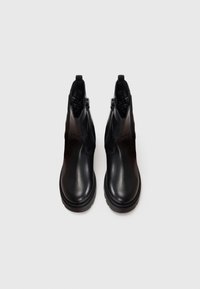 Bottines en cuir noir avec une texture lisse, bout arrondi, fermetures éclair sur les côtés et semelle en caoutchouc pour une meilleure adhérence.