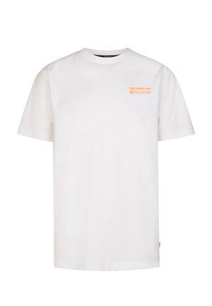 Blond kind staat, draagt een wit T-shirt, zwarte korte broek, witte sokken met zwarte strepen en witte sportschoenen op een effen achtergrond.