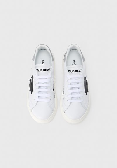 Baskets en cuir blanc avec accents noirs, présentant un logo imprimé, un bout arrondi et des semelles en caoutchouc plates. Design lacé avec une texture lisse.