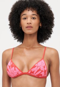 Triangel bikini topp med rosa og rød blomsterdesign. Har tynne justerbare stropper og en kontrastkant langs kantene.