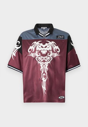 Chemise à manches courtes en tissu doux, avec un corps bordeaux à motif rayé, des accents noirs et une impression tribale blanche sur le devant.