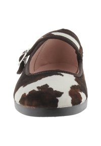 Zapato plano de estampado de vaca marrón y blanco con puntera redondeada, una correa con hebilla en tono plateado y un suave forro interior. Suela de goma negra.