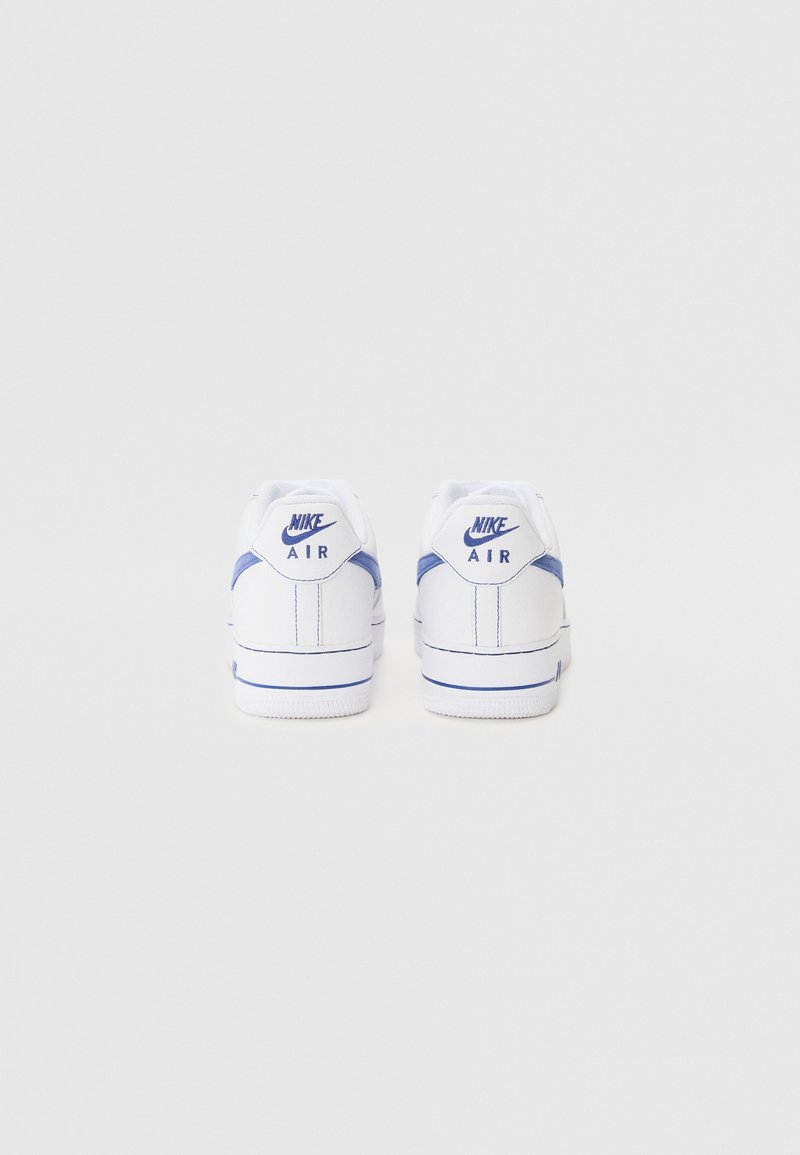 Baskets blanches en cuir avec des accents bleus, présentant un design bas, un col rembourré et une semelle en caoutchouc texturée. Logo Nike sur le talon.