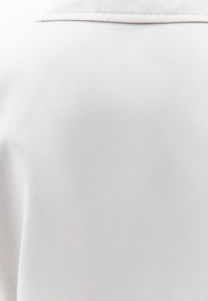 Witte stof met een gestructureerd oppervlak, voorzien van een subtiele glans en een klassieke kraagontwerp. Geen zichtbare hardware of accenten.