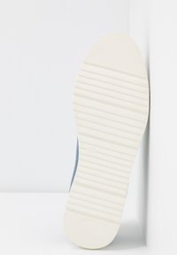 Semelle en toile bleue avec un fond en caoutchouc blanc. Présente des rainures horizontales pour l'adhérence et le numéro de taille 37 indiqué.