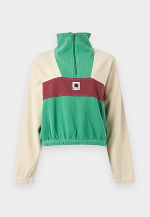 Augstu piegriezts vilnas džemperis ar rāvējslēdzēju, zaļš korpuss, krēmkrāsas piedurknes, bordo krūšu josla, elastīgs apakšmala un saules emblems uz krūtīm.