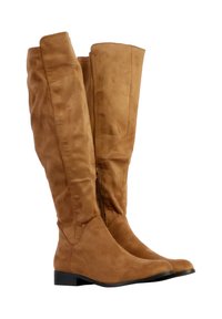 Høje kvinders ruskindsstøvler i tan med lave sorte hæle og sidelukkere, stående oprejst mod en hvid baggrund.