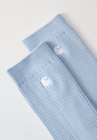 Calcetines de punto de color azul claro hasta la rodilla con detalle del logo bordado en la parte superior. Material suave con un acabado texturizado.