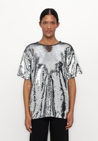 Storlekst-shirt i silver med paljetter, kort ärm och rund halsringning; slät, glänsande yta med reflekterande yta och en lätt drapering.