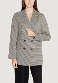 Blazer doppiopetto in tessuto a scacchi bianco e nero, con grandi bottoni neri e tasche laterali, caratterizzato da una vestibilità strutturata e maniche lunghe.