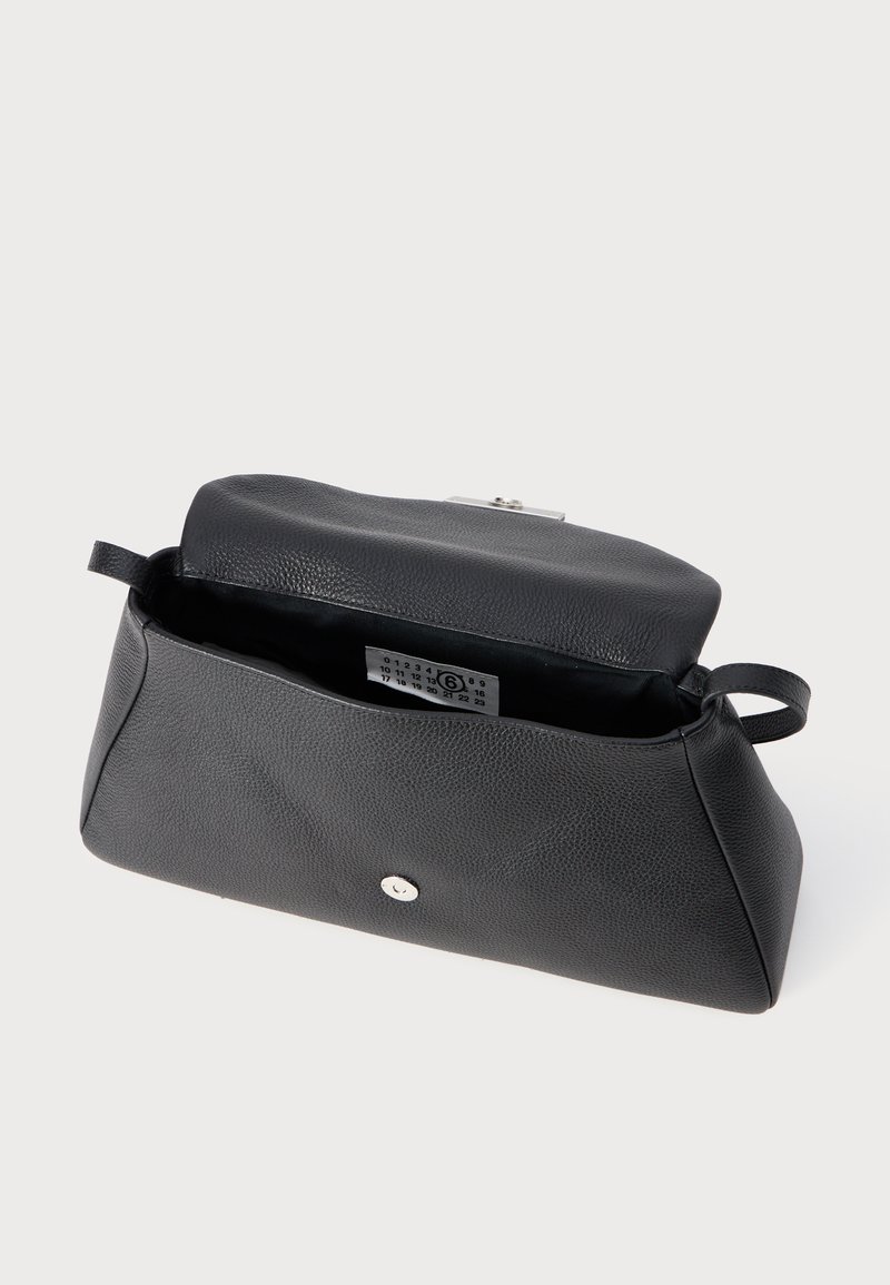 Zwarte leren clutch tas met textuur, flap open, zilveren sluiting en zichtbaar interieur label op witte achtergrond.