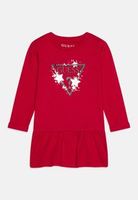 Czerwona sukienka z długim rękawem i rozkloszowanym dołem, z srebrnym nadrukiem logo w kształcie trójkąta oraz gwiazdkami na przodzie. Wykonana z miękkiej bawełny.