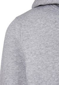 Gros plan sur la partie supérieure du dos d'un sweat à capuche gris chiné montrant la texture du tissu et les détails des coutures.