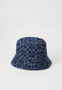 Navy denim bucket hat featuring a patterned texture, with a wide brim and a brand tag on the side. Exudes a casual style.