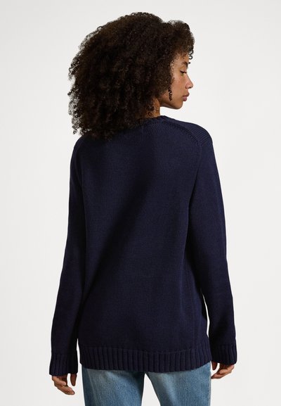 Námořnicky modrý pletený svetr s volným střihem, žebrovaným lemem a dlouhými rukávy. Vyrobený z měkkého, strukturovaného materiálu s kulatým výstřihem.