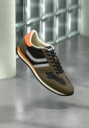 Sport sneaker in green and black suede and mesh with white and orange accents, featuring a cushioned sole and a textured finish.