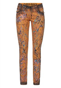 Jeans skinny en denim orange avec des éclaboussures de peinture bleue et rose, présentant un texte imprimé et des accents de chaîne décoratifs sur les poches avant.