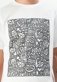Hvit bomull t-skjorte med svart grafisk design som har abstrakte former, ord og lekne illustrasjoner over hele fronten.