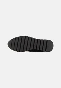 Suola di scarpe in gomma nera con gole profonde per la trazione, caratterizzata da strisce in rilievo e dettagli di branding incisi. Superficie testurizzata per una migliore aderenza.