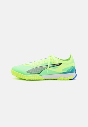 Neon groene atletiekschoenen met een ademend mesh bovenwerk, zwarte accenten, platte veters en een getextureerde rubberen zool met blauwe details.