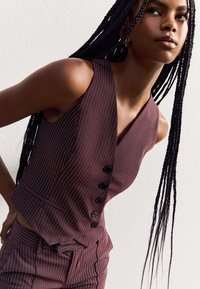 Burgundy pinstriped vest with a fitted design, five black buttons, and a sleek texture; paired with matching pants.