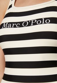 Bikini med svart och vit randig design och en figurnära passform. Har varumärkesnamnet "Marc O'Polo" och "EST. I STOCKHOLM" i vitt tryck.