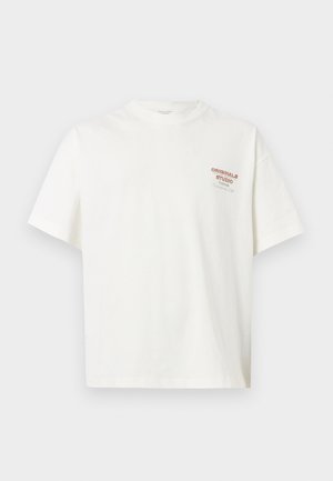 Bela kratka majica s kratkimi rokavi in okrolim izrezom z majhnim rdečim in črnim napisom »Originals Studio« na levi strani prsi.