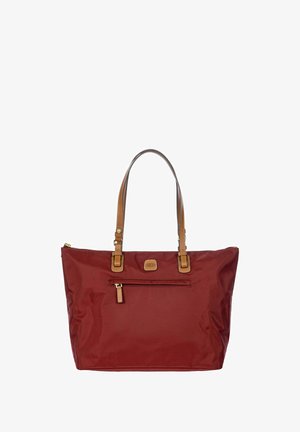 Sac fourre-tout en nylon rouge avec des poignées en cuir marron, doté d'une poche zippée à l'avant et d'un patch logo, de forme rectangulaire et avec une texture lisse.