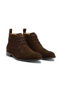 Brown suede ankle boots with narrow shape, lace-up design, and a small heel. Features a soft texture and subtle branding on the side.