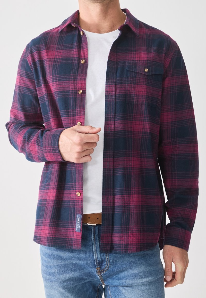 Camisa de franela en patrón de cuadros en tonos azul marino y burdeos, con diseño abotonado, bolsillo en el pecho y acentos de botones en color dorado.