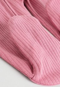 Rosafarbene, gerippte Socken aus weichem Material, mit einer runden Zehenpartie und einem strukturierten Strickdesign, das feine Rillen im gesamten Stoff aufweist.