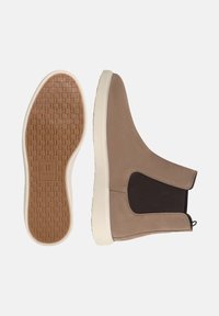 Nubukové členkové topánky v béžovej farbe s elastickými bočnými panelmi, bielymi gumovými podrážkami a textúrovanou hnedou podrážkou. Navrhnuté pre jednoduché obúvanie a pohodlie.