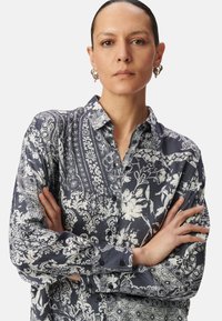 Camicia a maniche lunghe con bottoni, realizzata in tessuto blu navy con motivi floreali e paisley bianchi; con colletto, dalla vestibilità rilassata e dalla morbida consistenza.