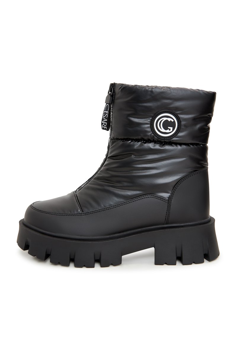 Botine negre până la gleznă cu un design căptușit, material sintetic lucios, închidere cu fermoar, talpă supradimensionată și detaliu circular cu logo pe latura exterioară.