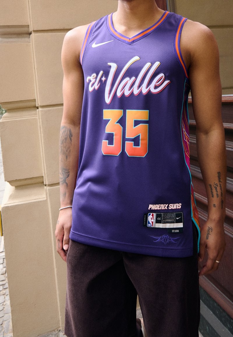 Personne portant un maillot de basket violet avec "El Valle" et le numéro 35, marquage des Phoenix Suns, avec des tatouages visibles sur le bras.