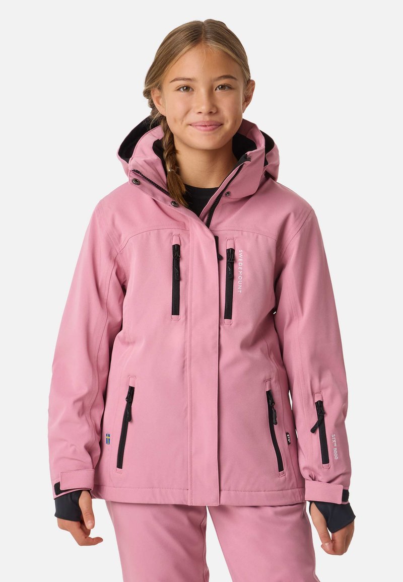 Veste imperméable rose avec une capuche bordée de noir, plusieurs poches zippées et des poignets élastiques. Présente un logo sur le côté gauche.