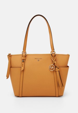 Tanfarvet læder Michael Kors taske med to skulderremme, udvendige sidelommer, guldfarvet logohængesmykke og en kvast som detalje.