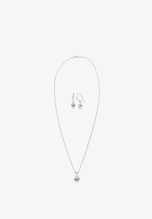 Zilveren halsketting met een enkele kristallen hanger; bijpassende oorbellen hebben kleine kristaldruppels. Slank ontwerp met een fijne ketting.
