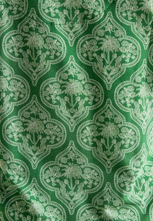 Zelená látka s květinovým vzorem, obsahující motivy palem a květin, orámovaná složitými bílými vzory a tečkovanými akcenty.