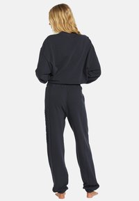 Mørkegrå sweatshirt og matchende sweatpants, begge i blødt stof med en afslappet pasform. Bukserne har en elastisk talje og ribbede manchetter.
