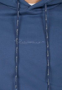 Felpa blu navy con tessuto testurizzato, dotata di tasca frontale, coulisse regolabile e logo ricamato in azzurro.