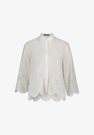 Biała bluzka z kołnierzykiem, długimi rękawami i misternym falistym dołem z wyciętymi kwiatowymi wzorami. Wykonana z lekkiego materiału.